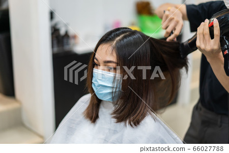 hairdresser using hair dryer and comb to the hair 66027788