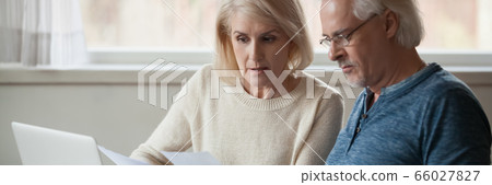 Aged couple read bank statement analyzing family expenses feels concerned Aged couple read bank statement analyzing family expenses feels concerned 66027827