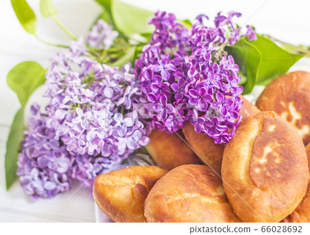 Piroshki - russian baked puff pastry with cabbage fillings and bouquet of lilacs. Traditional russian cabbage stuffed baked pastry. lean pies with cabbage. Beautiful homemade cakes with cabbage 66028692