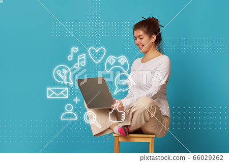 Woman is siting in lotus position on a chair with a laptop. 66029262