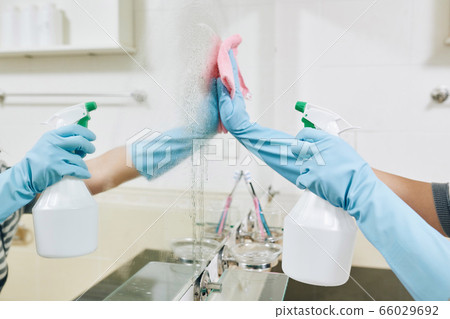 Woman cleaning bathroom mirror Woman cleaning bathroom mirror 66029692