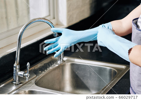 Housewife putting on rubber gloves Housewife putting on rubber gloves 66029717