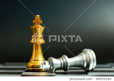 Gold king chess piece win over lying down silver king on black background Gold king chess piece win over lying down silver king on black background 66030264