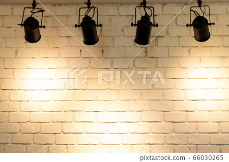 Hanging spotlight illuminate at brick wall background with copy space Hanging spotlight illuminate at brick wall background with copy space 66030265