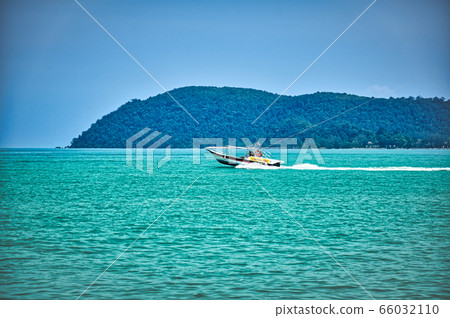 Speed boat on the waves of the azure Andaman sea under the blue sky near the shores of the sandy beautiful exotic and stunning Cenang beach in Langkawi island, 66032110