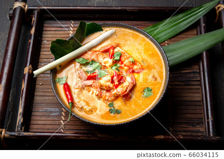 Shrimps Tom Yam Kung in grey bowl with thai spices on autentic tray top view, wooden background. Shrimps Tom Yam Kung in grey bowl with thai spices on autentic tray top view, wooden background. 66034115