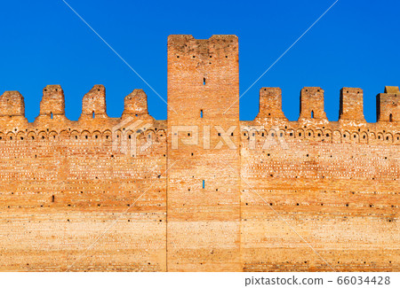 Old brick wall of medieval Italian fortress against the blue sky 66034428