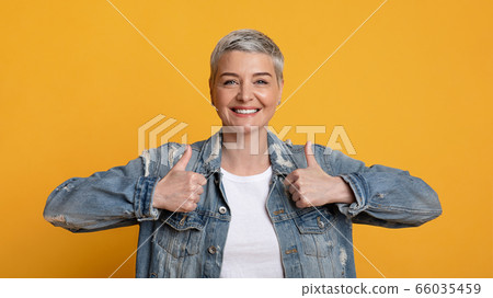 Portrait of happy mature woman showing thumbs up and widely smiling Portrait of happy mature woman showing thumbs up and widely smiling 66035459