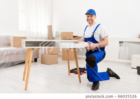 Handyman Installing Wooden Desk Working Indoors, Smiling To Camera 66035526