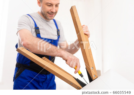 Repairman Assembling Table Using Screwdriver Working Standing Indoors Repairman Assembling Table Using Screwdriver Working Standing Indoors 66035549