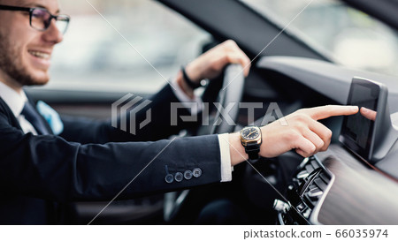 Businessman In Specs Sitting In New Auto Checking Dashboard Businessman In Specs Sitting In New Auto Checking Dashboard 66035974