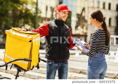 Girl Receiving Restaurant Food Order From Courier On Bike Outdoors 66035978