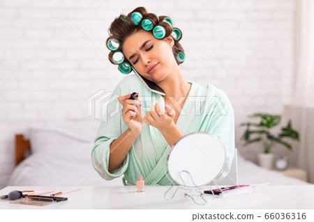 Discontented Housewife Talking On Cellphone Doing Manicure At Home Discontented Housewife Talking On Cellphone Doing Manicure At Home 66036316