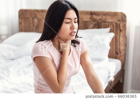 Japanese Woman Suffering From Sore Throat Pain Sitting In Bedroom Japanese Woman Suffering From Sore Throat Pain Sitting In Bedroom 66036365