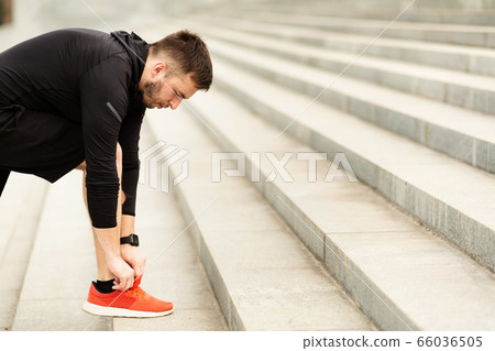 Closeup of Young Man Tying Sports Shoe In City 66036505