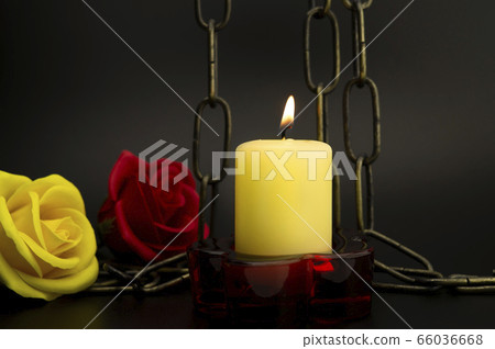 Burning yellow candle, chain and two roses Burning yellow candle, chain and two roses 66036668