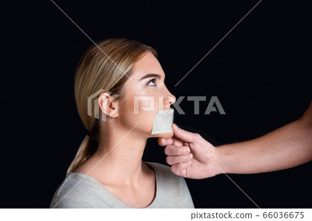 Discrimination and tyranny. Man seals woman mouth with tape Discrimination and tyranny. Man seals woman mouth with tape 66036675