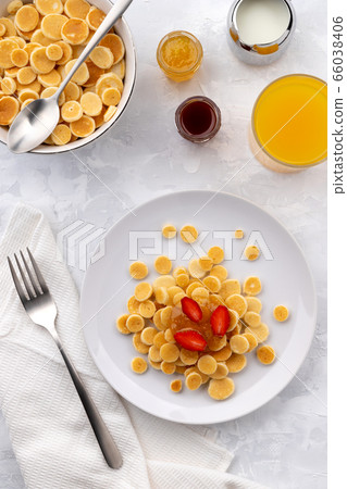 Tiny mini pancake cereal. Home made breakfast with raspberries, jam and juice on gray background 66038406
