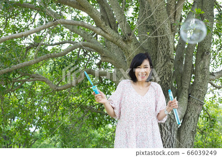 Refreshing middle woman health image under big tree soap bubbles 66039249