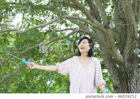 Refreshing middle woman health image under big tree soap bubbles 66039252