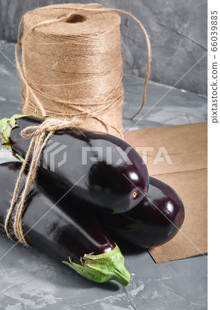 Eggplant on a gray background, behind paper bags and heather for packaging. Vegetable delivery, photo for online stores with delivery. 66039885