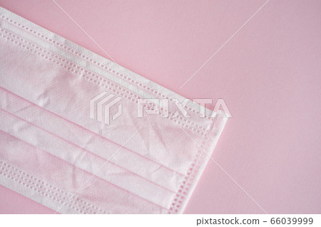 Used pink medical mask on a pink background. Disposable 3-ply medical mask to cover the mouth and nose to prevent coronavirus. Coronavirus quarantine. Antivirus medical mask for protection covid-19. 66039999