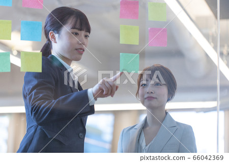 Woman meeting while looking at sticky notes Woman meeting while looking at sticky notes 66042369