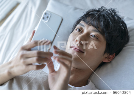 Young man looking at smartphone in futon 66043804