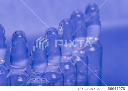 Glass medical ampoule vial for injection. Medicine is liquid sodium chloride with of aqueous solution in ampulla. Close up. Bottles ampule multicolor. Glass medical ampoule vial for injection. Medicine is liquid sodium chloride with of aqueous solution in ampulla. Close up. Bottles ampule multicolor. 66043978