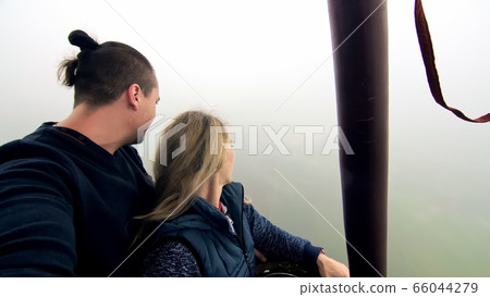 Adventure love couple on hot air balloon watermelon. Man and woman kiss hug love each other. Burner directing flame into envelope. Happy people. 66044279