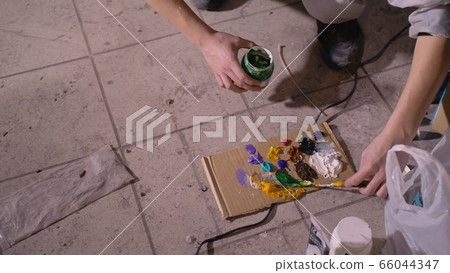 Artist designer draws an eagle on the wall. Craftsman decorator paints picture with acrylic oil color. Painter painter dressed in paint coat. Indoor. 66044347