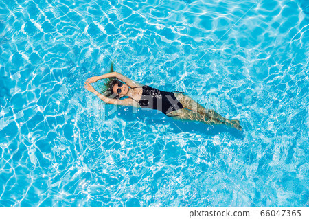 Woman in sunglasses swims in the pool Woman in sunglasses swims in the pool 66047365