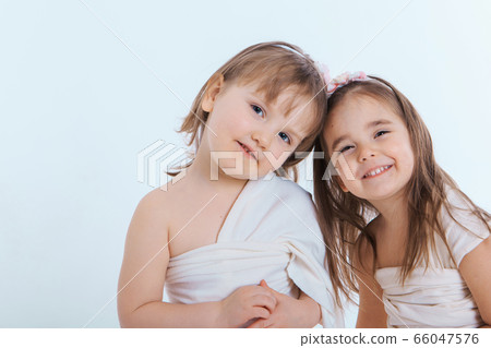 two little happy girls smiling on white background. Portrait of children hugging. The concept of relationships in the family, friends, sisters, couple in love. Copy space 66047576