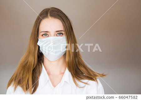 Portrait of a woman on a beige background, who wears a medical mask. Demonstration of medical equipment. Portrait of a woman on a beige background, who wears a medical mask. Demonstration of medical equipment. 66047582