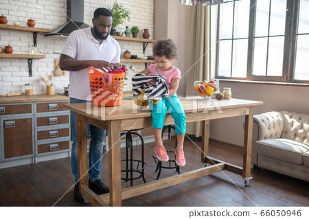 Dark-skinned tall father and his cute daughter speding time at home daling with housework 66050946