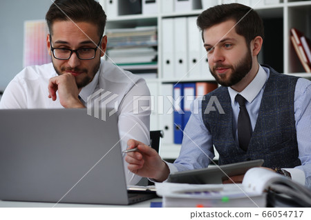 Handsome males looking at screen of laptop Handsome males looking at screen of laptop 66054717