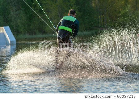 Wakeboarder making tricks. Low angle shot of man wakeboarding on a lake. 66057218