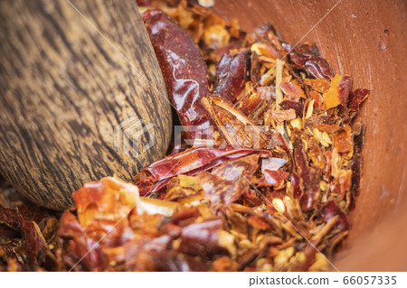 Pound dried red chillies in a mortar Pound dried red chillies in a mortar 66057335