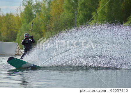Wakeboarder making tricks. Low angle shot of man wakeboarding on a lake. Wakeboarder making tricks. Low angle shot of man wakeboarding on a lake. 66057340