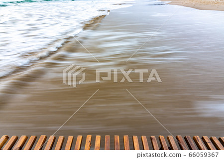 Sea surf rolling ashore after sunset, blurry with 66059367