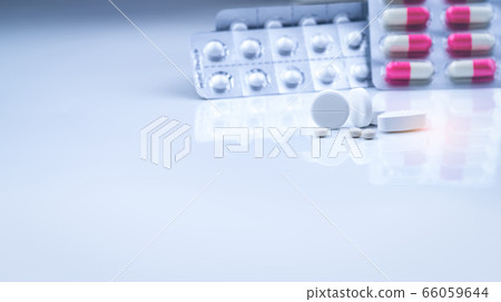 White tablets pills on blurred white-pink capsules 66059644