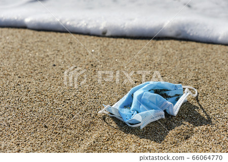 used surgical mask thrown on the sand of a beach used surgical mask thrown on the sand of a beach 66064770