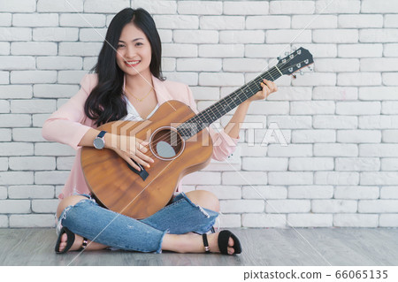 young woman playing guitar in living room, Enjoying carefree time at home. young woman playing guitar in living room, Enjoying carefree time at home. 66065135