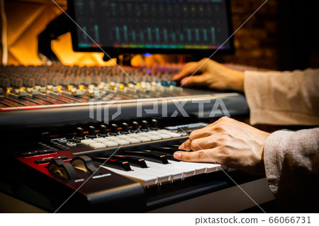 music producer hands arranging a song on midi keyboard in home recording studio 66066731