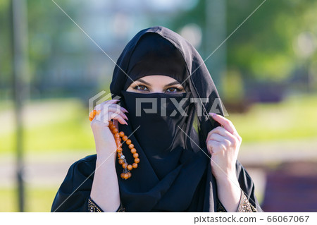 Muslim woman stands with rosary Islamic scores. Muslim woman stands with rosary Islamic scores. 66067067