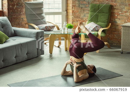Sporty young woman practicing yoga at home Sporty young woman practicing yoga at home 66067919