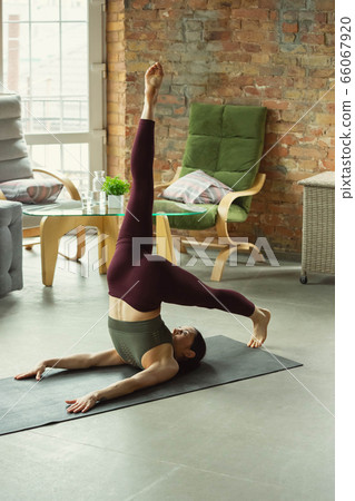 Sporty young woman practicing yoga at home Sporty young woman practicing yoga at home 66067920