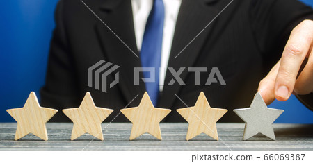 Businessman points to the fifth star. The concept of the rating of hotels and restaurants. The evaluation of visitors. Quality level, good service. Best customer rating. Feedback. Satisfaction 66069387