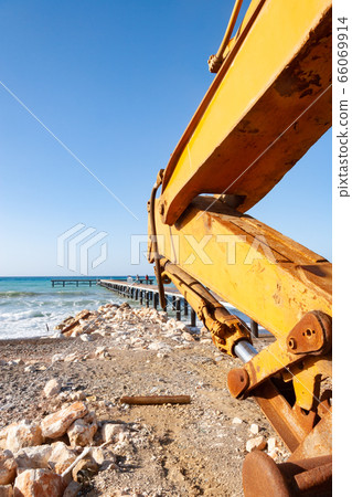 Scoop of an excavator set against a pier at the Scoop of an excavator set against a pier at the 66069914