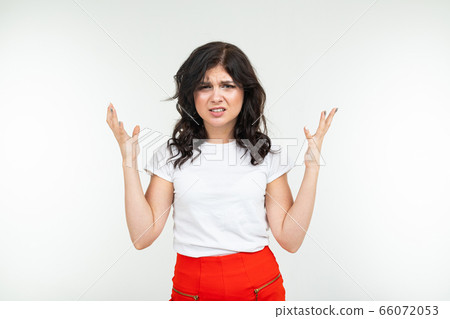 indignant brunette girl in a white tank top fed up on a white studio background indignant brunette girl in a white tank top fed up on a white studio background 66072053